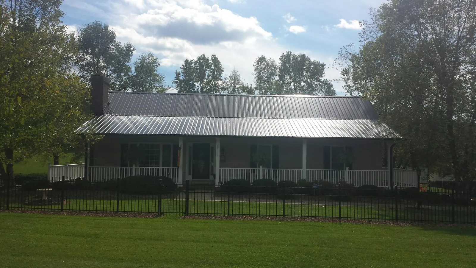 Gray metal roof on a brick ranch with a full width front porch — Gutter Guard Installation work by our crew in Union